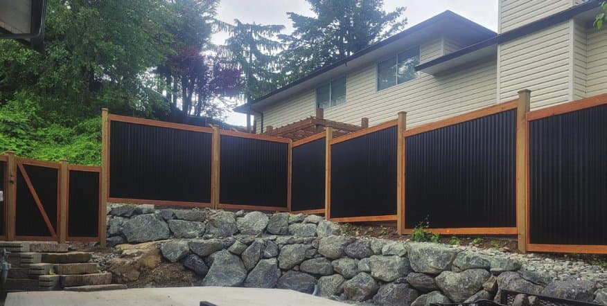 Wood and steel fence — black corrugated panels in a wood frame, installed